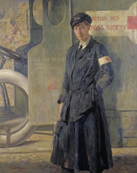 A VAD ambulance driver standing by the cab of her vehicle in uniform. She has her left hand in the pocket of her skirt and an oil can in her right hand. Though her pose is casual, her eyes stare out at the viewer. The debris of bomb damaged buildings is visible in the background to the left.